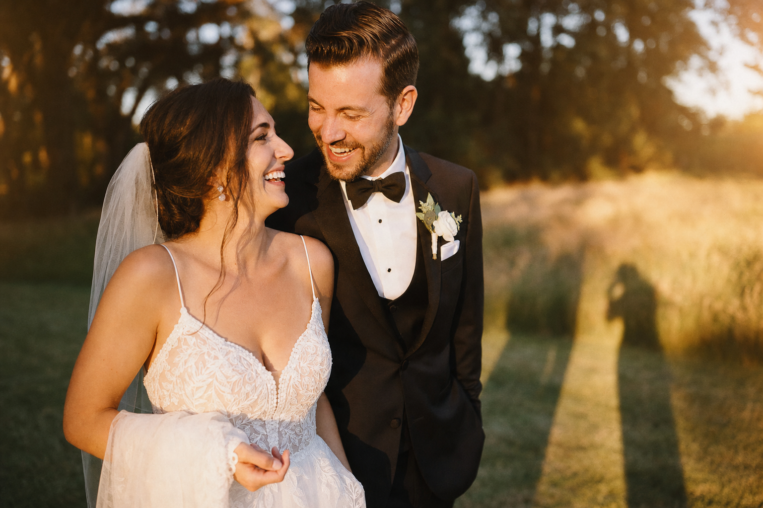 Photographe capturant un couple de mariés riant à la lumière dorée